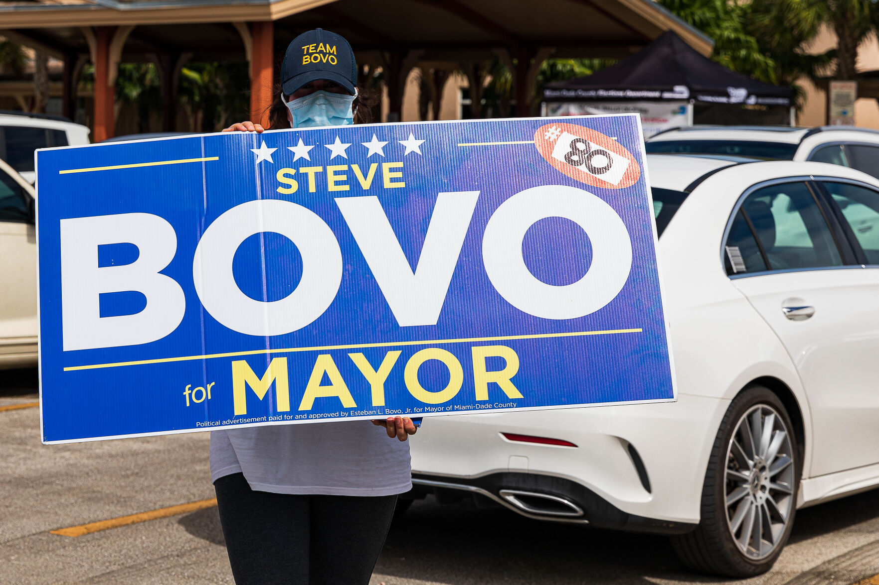 Raquel Hernandez holds a Steve Bovo for Mayor sign in the Community Center parking lot on Monday afternoon.